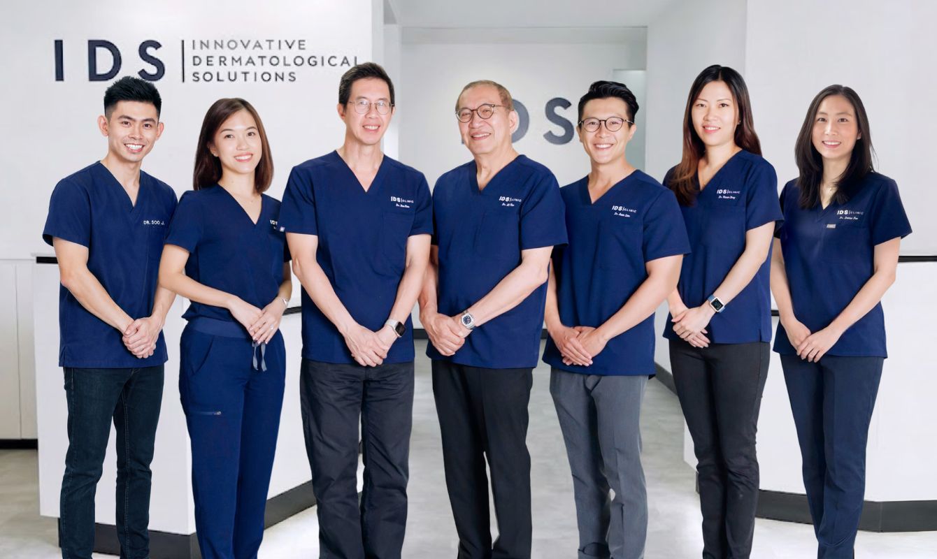 A group of healthcare professionals standing together, all wearing navy scrubs, in a modern clinic environment.