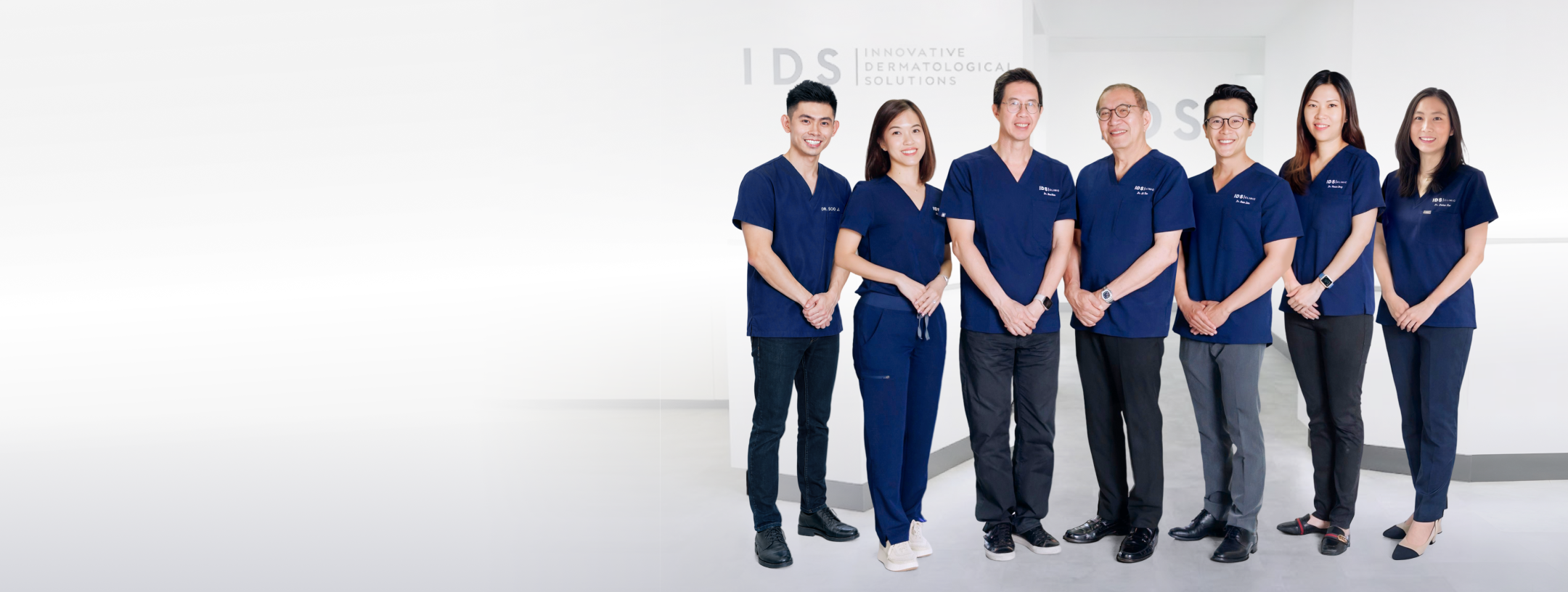 A group of medical professionals in navy blue scrubs standing together in a modern clinic space.